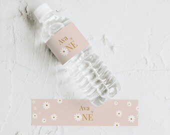 May include: Pink and white water bottle labels with a daisy pattern and the text "Ava is One" in gold lettering.