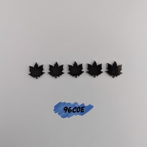May include: Five dark brown maple leaf-shaped embellishments are arranged horizontally on a white background. A blue brushstroke with the text "96COE" is below the leaves. The leaves have detailed veining.