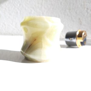 May include: A light green, white, and brown marble ring holder with a unique, faceted design.
