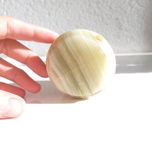 May include: A smooth, round, green and white, polished, natural stone sphere.