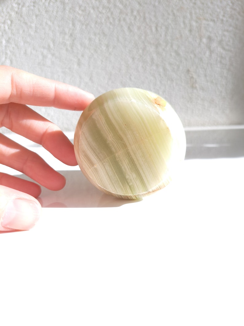 May include: A smooth, round, green and white, polished, natural stone sphere.