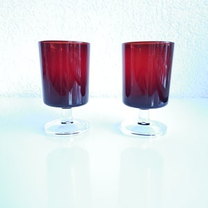 Può includere: Due bicchieri da vino in vetro trasparente con gambo e una tonalità rosso intenso.