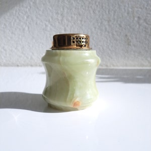 May include: A green marble bottle stopper with a gold top. The bottle stopper has a textured surface and a round shape.