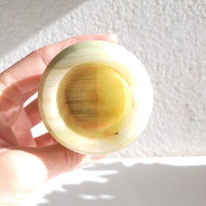 May include: A small, round, green and white onyx bowl with a smooth, polished surface.