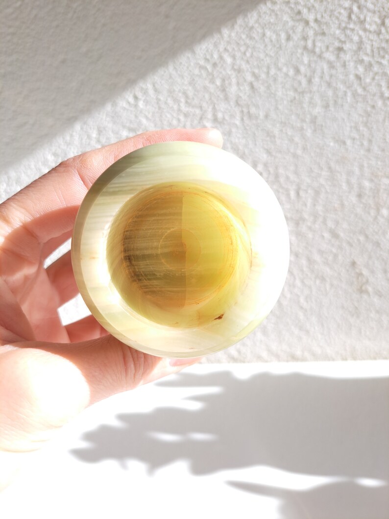 May include: A small, round, green and white onyx bowl with a smooth, polished surface.