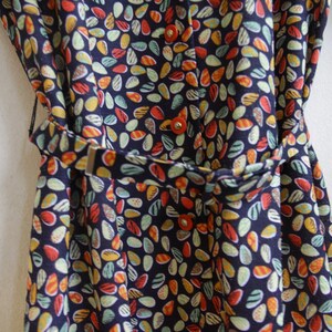 May include: A navy blue dress with a colorful abstract print of small, teardrop-shaped patterns. The dress has a belt and buttons.