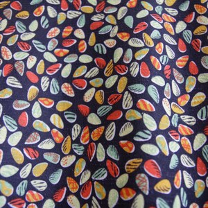 May include: A dark blue fabric with a repeating pattern of colorful, abstract shapes resembling seeds or leaves. The shapes are in shades of red, yellow, green, and white.