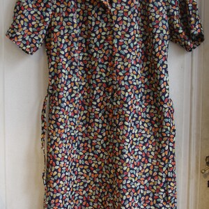 May include: A short-sleeved dress with a button-up front and a collar. The dress is made of a dark blue fabric with a pattern of small, colorful leaves.