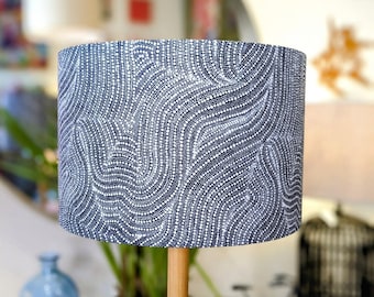 May include: A white and blue patterned lampshade with a wooden base. The pattern is made up of small white dots on a dark blue background, creating a swirling design.