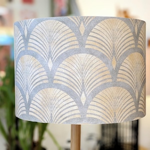 May include: A grey and beige lampshade with a geometric pattern of overlapping arches. The pattern is reminiscent of Art Deco style.