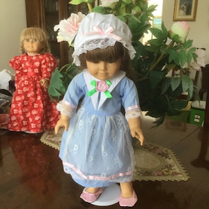 For an 18” doll like Felicity,a blue Colonial era dress with pink and white lace apron and trim and white mob cap, plus pink satin slippers