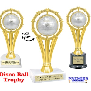 May include: A gold-colored trophy with a spinning disco ball on top. The base of the trophy is white and has the text "Free Engraving Up to 2 Lines".