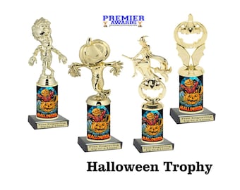 May include: Four gold Halloween trophy options with different character toppers. The toppers include a zombie, a scarecrow, a witch riding a broomstick, and a jack-o-lantern. Each trophy has a black base and a cylindrical column with a Halloween-themed design. The text "Free Engraving Up to 2 Lines" is on each base.