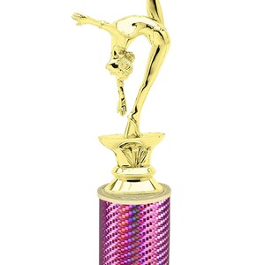 May include: Gold-colored trophy with a gymnast figurine on top. The base is a pink column with a white base. The base has the text "Free Engraving Up to 2 Lines".