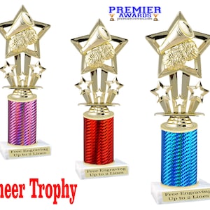 May include: Three cheerleading trophies with gold star and megaphone toppers. The trophy bases are cylindrical and wrapped in pink, red, and blue patterned paper. Each trophy sits on a white base with text that reads "Free Engraving Up to 2 Lines". The words "Cheer Trophy" are in red.