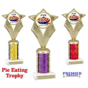 May include: Three gold star-shaped trophy bases with a pie eating contest theme. The trophies have a purple, red, and yellow base with a free engraving option up to two lines. The trophies are on a white surface.