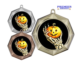 Peut inclure: Trois médailles hexagonales aux finitions argent, bronze et or, chacune présentant un insert circulaire central avec un graphique d'une main squelettique tenant une citrouille orange vif sur fond noir. Le texte PREMIER AWARDS est visible.