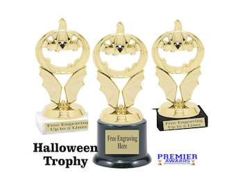 Peut inclure: Trois trophées dorés d'Halloween avec des sommets en forme de citrouille et des détails d'ailes de chauve-souris. Chaque trophée a une base pour la gravure. Le texte "Halloween Trophy" est affiché en dessous.