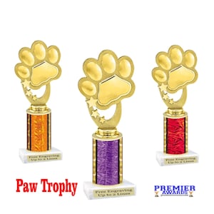 May include: Three gold paw print trophies with different colored bases. The bases are orange, purple, and red. Each trophy has the text "Free Engraving Up to 2 Lines" on a white base.