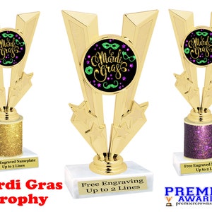 May include: Gold trophy with a Mardi Gras theme. The trophy has a black circle with green and purple Mardi Gras masks and the words "Mardi Gras" in green letters. The base of the trophy is gold glitter.