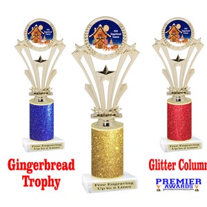 May include: Three gold gingerbread house trophy awards with glitter columns. The columns are blue, gold, and red. Each trophy has a free engraving option up to two lines.