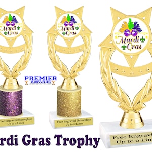 May include: Gold Mardi Gras trophy with a star-shaped base and a wreath design. The trophy has a purple, gold, or white base with glitter. The trophy features a white circle with a Mardi Gras mask and the text "Mardi Gras".