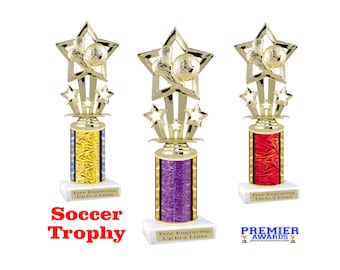 May include: Three gold soccer trophy awards with a star design and a soccer ball. The base of each trophy is a different color: yellow, purple, and red. Each trophy has the text "Free Engraving Up to 2 Lines".