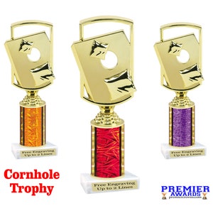 May include: Gold cornhole trophy with a red, orange, and purple base. The trophy features a gold cornhole board with a hole in the center. The base has a textured design. Free engraving up to 2 lines.