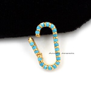 May include: Gold-toned earring with a turquoise blue enamel design. The earring is shaped like a small oval with a hook closure.