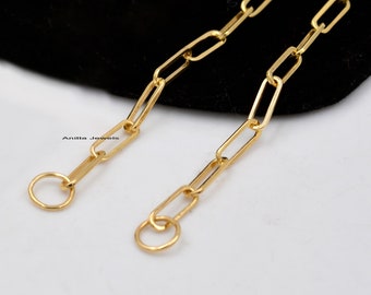 May include: A gold chain necklace with a simple, rectangular link design. The chain has two round clasps at the ends.