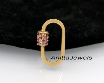 May include: Gold-toned metal charm with a U-shaped design and a cylinder-shaped section with multi-coloured gemstones. The charm is on a black background. AnittaJewels is written in white text on the background.