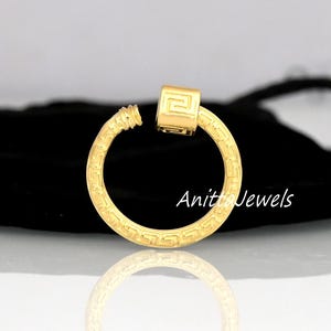 May include: A gold-colored earring with a geometric design and a square accent. The earring is a hoop shape with a screw-on closure. The text "Anita Jewels" is visible on the image.