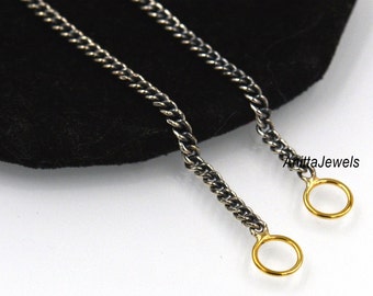 May include: Two silver chains with gold jump rings at the ends. The chains are on a black background.