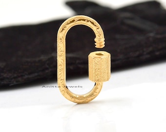 May include: Gold-toned metal lobster clasp with an ornate design. The clasp is oval-shaped and has a textured finish.