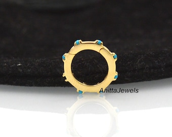 May include: Gold hoop earring with a hinged closure and turquoise accents. The earring is on a black background.
