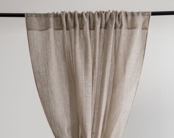 Könnte beinhalten: Beige Leinen-Vorhangpaneel, unten geknotet. Der Vorhang hängt an einer schwarzen Stange vor einer weißen Wand. Ein Zweig mit Grün ist unten rechts zu sehen. Der Vorhang besteht aus leichtem, luftigem Stoff.