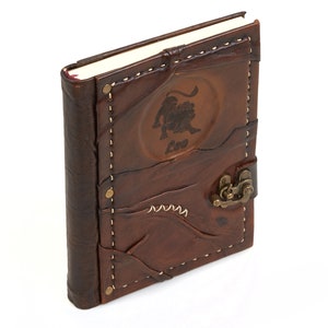 May include: Brown leather journal with a stitched design and a brass clasp. The front cover features an embossed lion with the word "Leo" underneath.