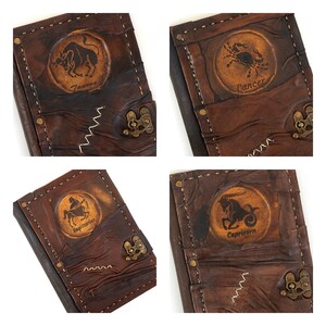May include: Four brown leather journals with zodiac signs embossed on the front. The signs are Taurus, Cancer, Sagittarius, and Capricorn.