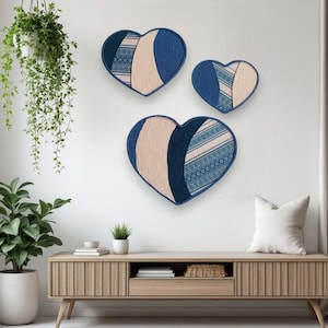 Könnte beinhalten: Drei blaue und cremefarbene Herz-Wanddekorationen mit geometrischen Mustern. Die Herzen sind versetzt an einer weißen Wand angeordnet.