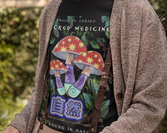 May include: Black t-shirt featuring a mushroom graphic with the text "SACRED MEDICINE" and Japanese characters. The design includes red, purple, and white mushrooms with star accents. The shirt is worn with a brown cardigan and suspenders.