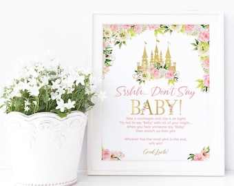 Puede incluir: Un cartel imprimible rosa y dorado con un borde floral y una ilustración de un castillo. El cartel dice "Ssshh... No digas BEBÉ!" e incluye instrucciones para un juego.