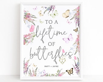 May include: A white framed print with a watercolor floral border and butterflies. The text reads "To a lifetime of butterflies" with the names Matt + Jayne below.
