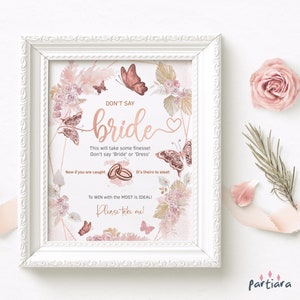 Può includere: Un cartello di gioco per la festa di addio al nubilato stampabile con un design floreale rosa e oro. Il cartello dice "Non dire sposa" e include le istruzioni per un gioco in cui gli ospiti cercano di rubare gli anelli.