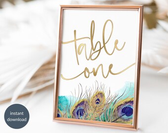 May include: Gold foil table number one with a watercolor background of peacock feathers in shades of teal, green, and purple.