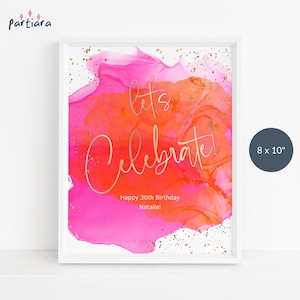 Op de afbeelding: Abstracte aquarelprint in roze en oranje met gouden glitter. De tekst "Let's Celebrate!" is geschreven in gouden schrift. De tekst "Happy 30th Birthday Natalie!" is in zwart onder de hoofdtekst geschreven. De print is 20,3 x 25,4 cm.