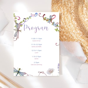 Op de afbeelding: Een witte programmakaart met aquarel illustraties van libellen, vlinders en bloemaccenten. Het woord "Program" is geschreven in een paars scriptlettertype. Het schema bevat tijden voor aankomst van gasten, spellen, lunch en cake.