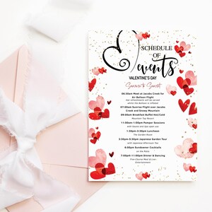 Peut inclure: Une carte blanche avec un programme d'événements pour la Saint-Valentin. La carte est décorée de cœurs rouges et roses et de paillettes dorées. Le texte sur la carte indique "Programme des événements Saint-Valentin Lever du soleil au coucher du soleil" et liste une variété d'activités, notamment un vol en montgolfière, une visite d'un jardin japonais et un dîner de cinq plats avec danse.