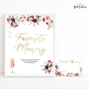 May include: A white framed sign and notecard with the words "Favorite Memory" in gold script. Floral arrangements in shades of pink and burgundy decorate the top and bottom. A champagne glass illustration is also included.