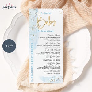 May include: A baby shower menu card, 4 x 9 inches, with a blue and gold design. The menu lists food items like pastries, cheese, fruits, and hot breakfast options. The text reads "A Sweet Baby Celebration!"