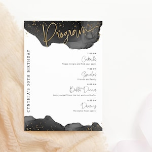 May include: A black and gold birthday party programme with a watercolour background and gold glitter. The programme lists the schedule for the event, including cocktails, speeches, buffet dinner, and dancing.